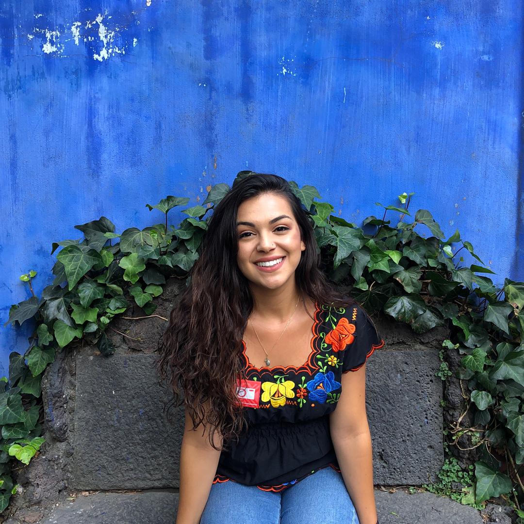 samantha sitting on a bench with a flower shirt and smiling